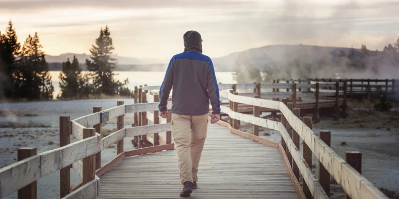 twilight environment man walking across bridge towards lake enviroment