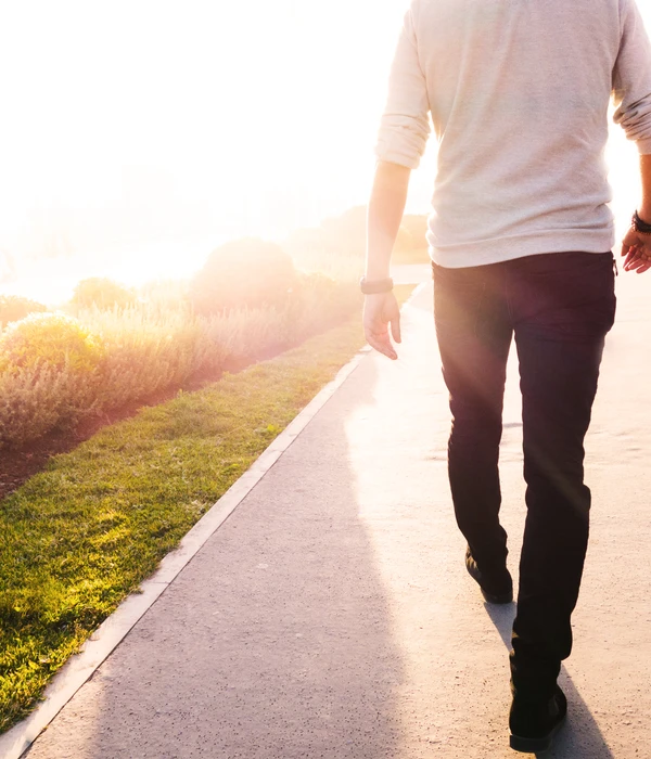 twilight environment man walking sidewalk sun shining through grass