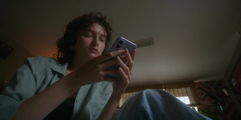 twilight internet addiction woman sitting bed holding cell